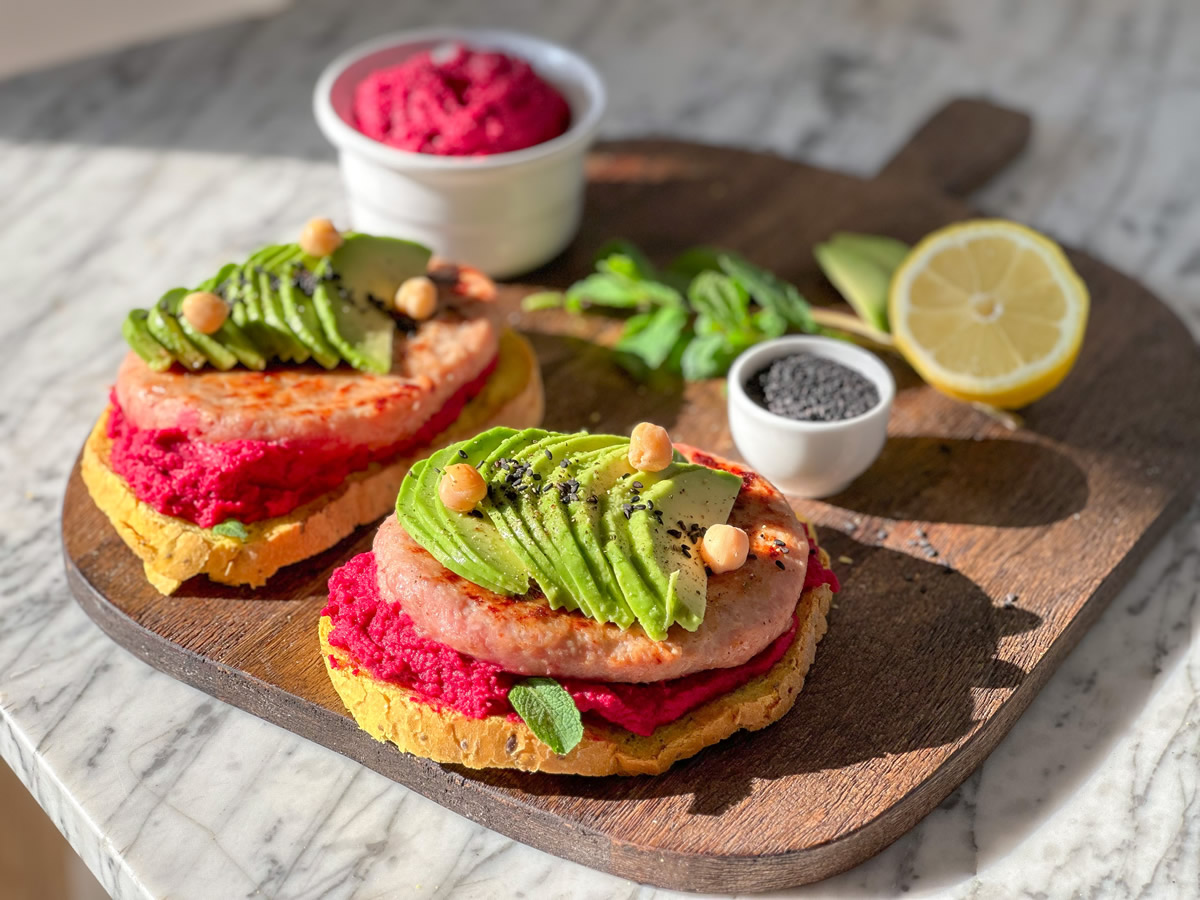 Hamburger di pollo gourmet con hummus di barbabietola e avocado