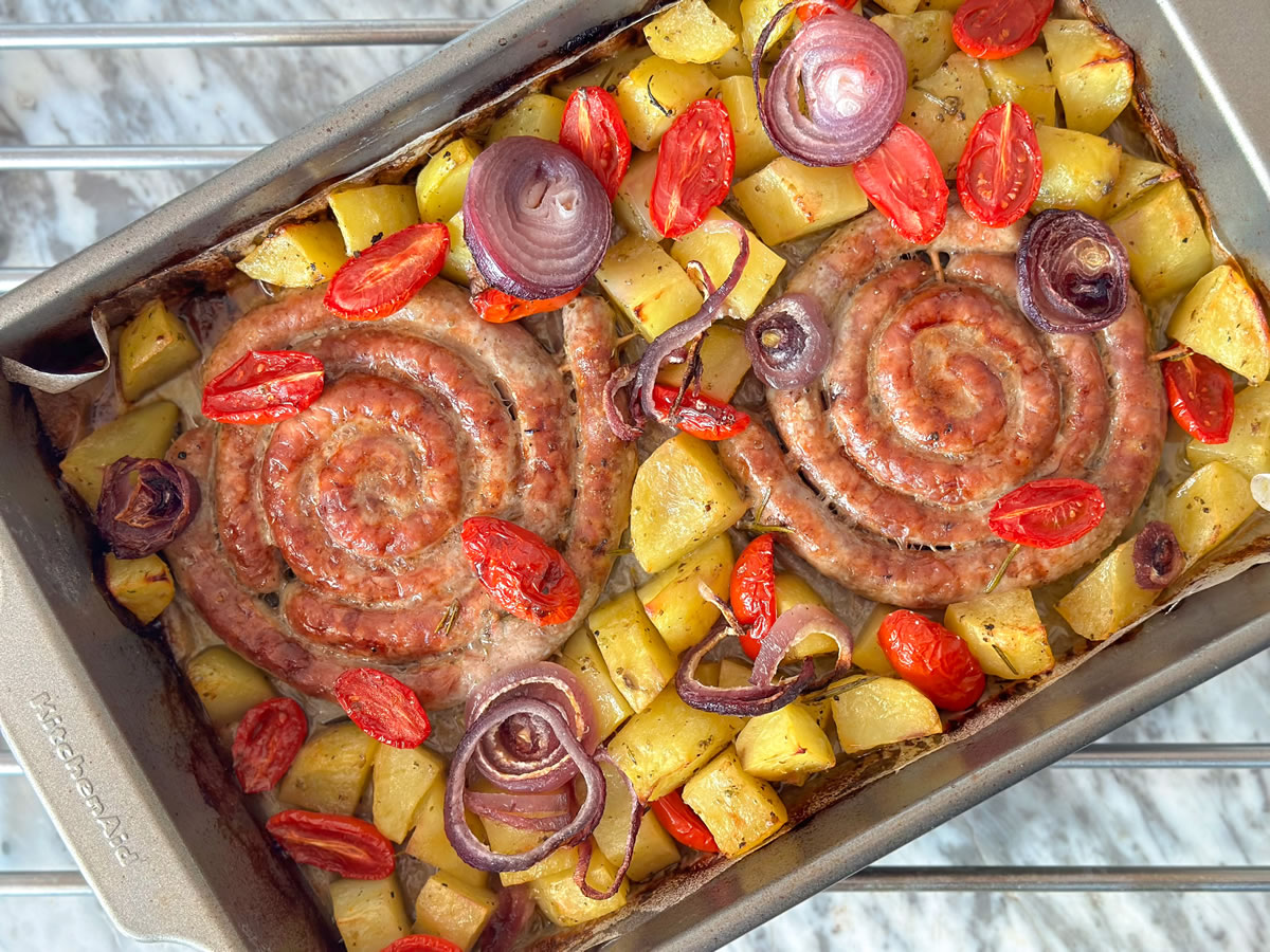 Luganega di suino al forno con patate, cipolle e pomodorini